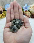 Hand holding one ounce of labradorite chips