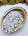 Three ounces of howlite crystal chips on abalone shell