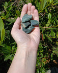 Hand holding four rough bloodstone crystal stones
