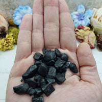 hand holding 1 ounce of black tourmaline crystal chips