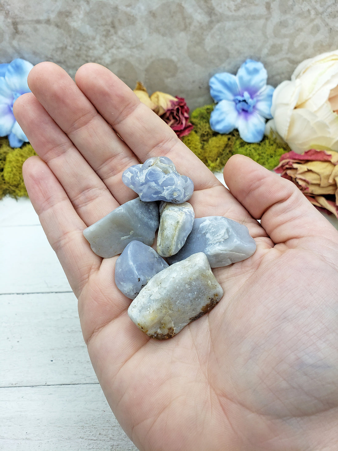 hand holding tumbled fancy blue chalcedony