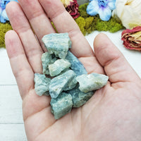 rough aquamarine stones in hand