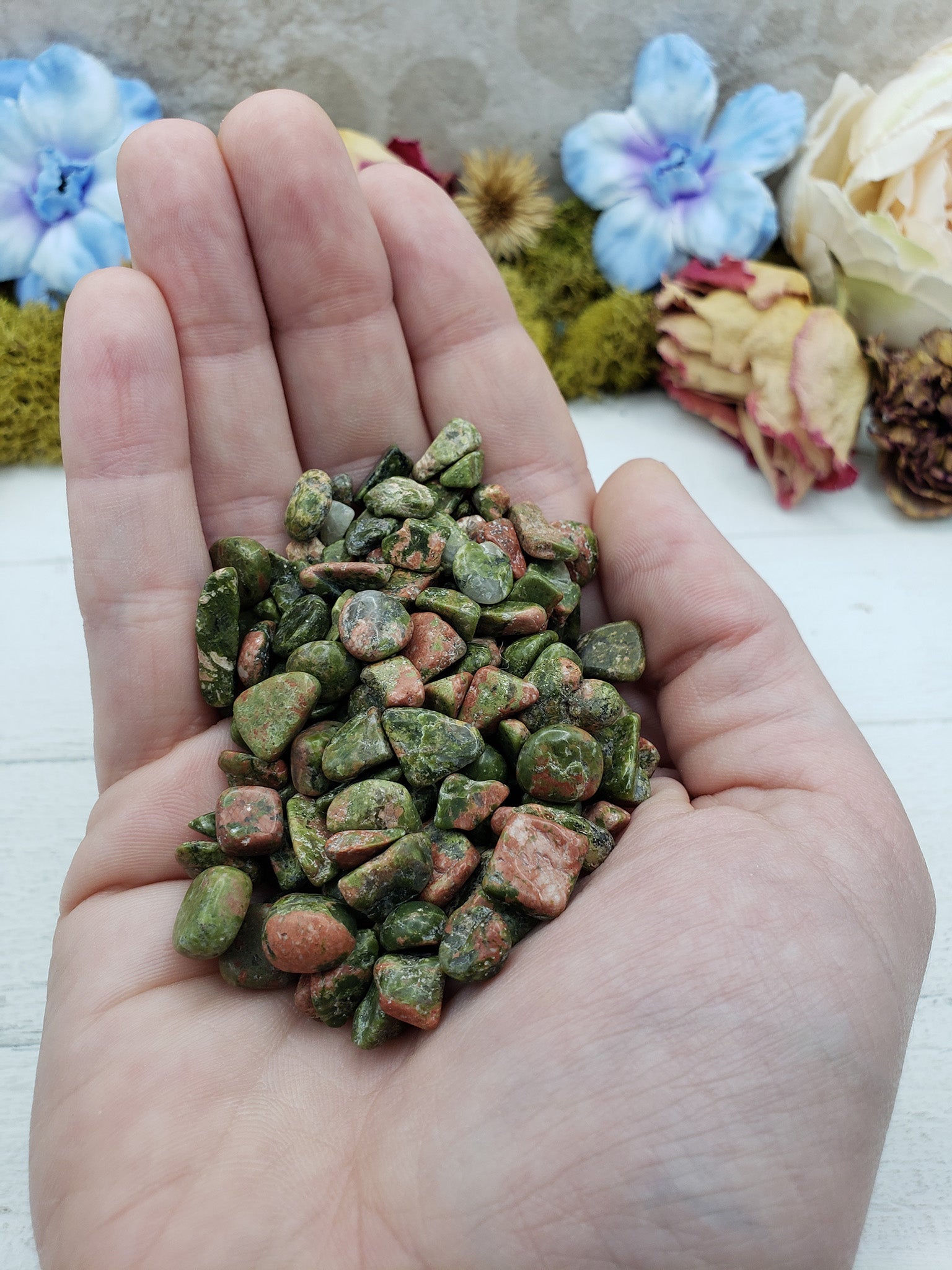 hand holding 3 ounces of unakite chips