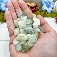 hand holding tumbled aquamarine crystal pieces
