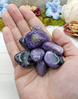 hand holding charoite stone pieces