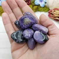 hand holding charoite stone pieces