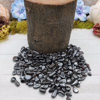 tumbled mini hematite chips by a wooden prop log