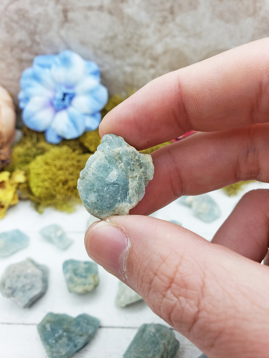 rough aquamarine stone between fingers