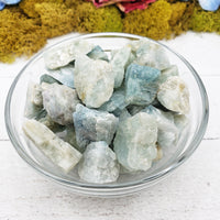 rough aquamarine stones in glass bowl