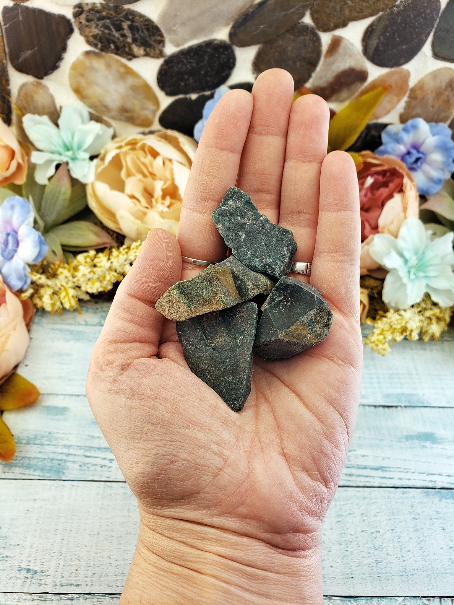 Hand holding rough bloodstone crystal pieces