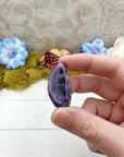 hand pinching charoite gemstone