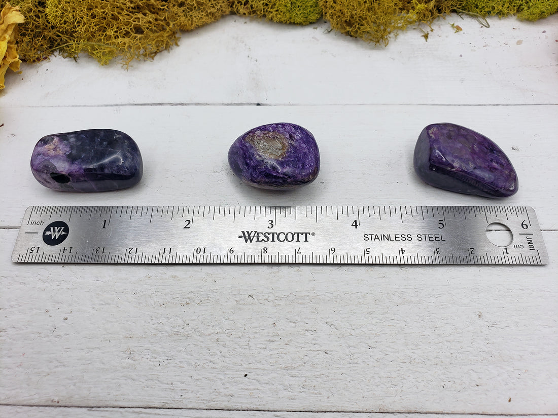ruler comparing size of three charoite stones