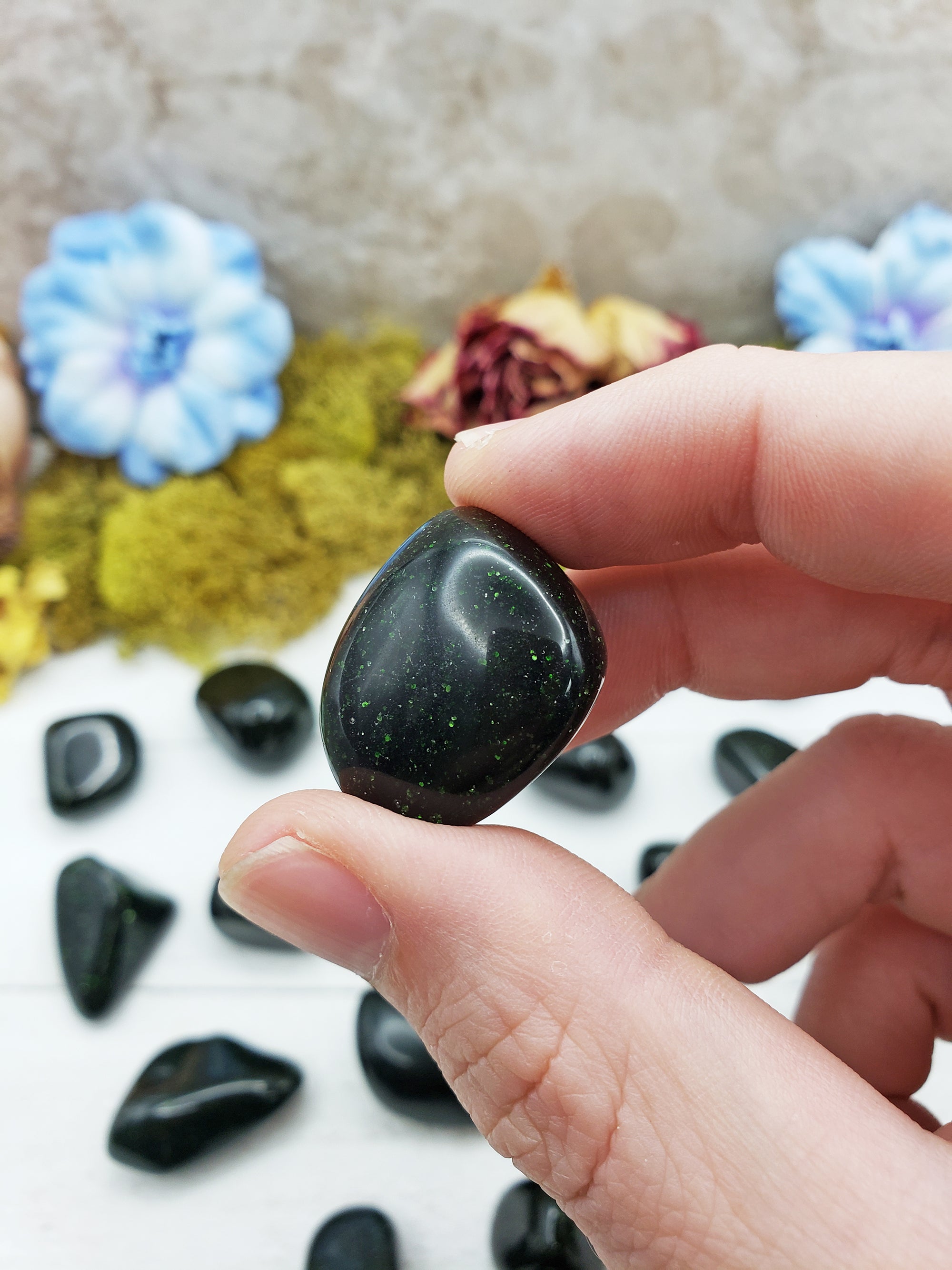 green goldstone crystal between fingers