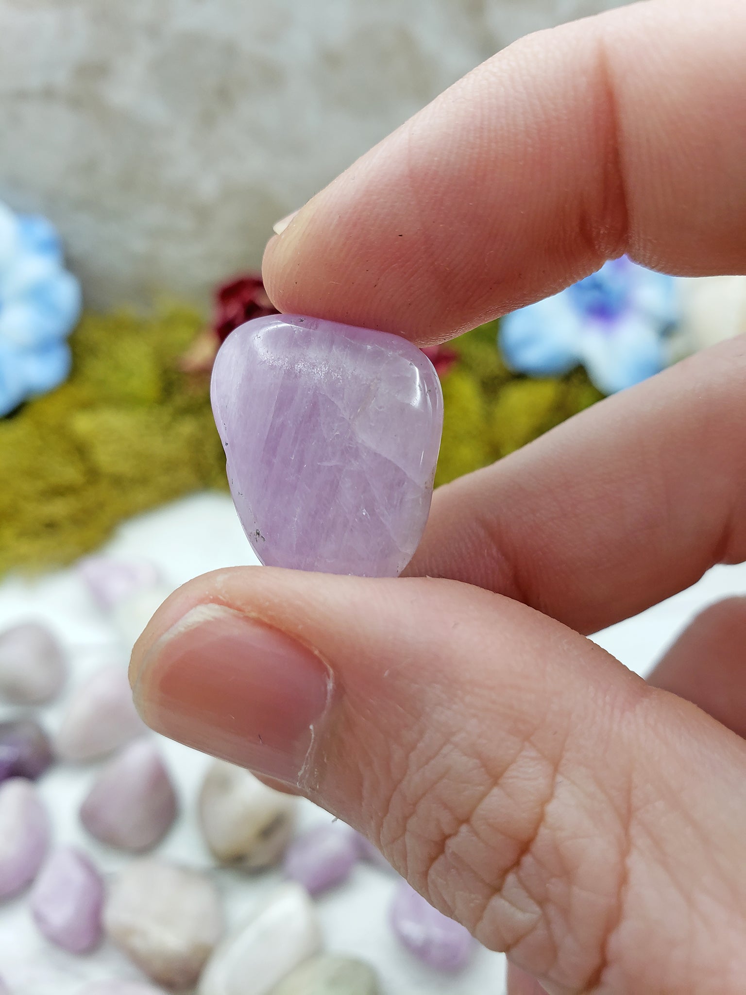 hand pinching kunzite stone between fingers