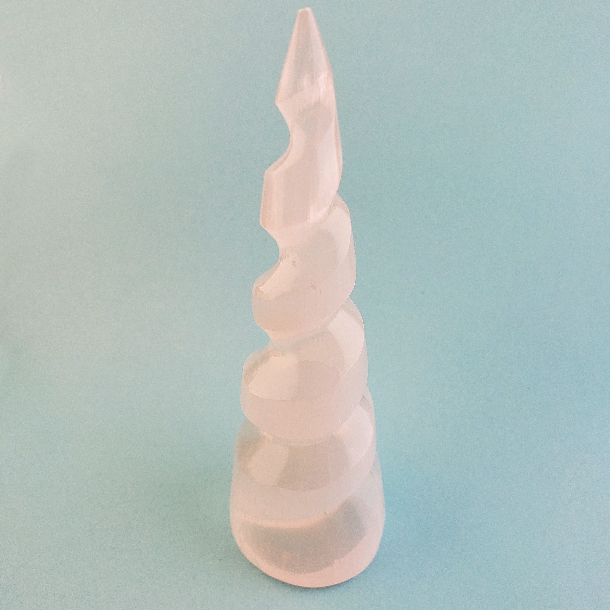 White Selenite Unicorn Horn Spiral Crystal Tower - One 5.5 Inch Tower - On Blue Background