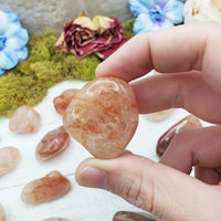 light strawberry quartz stone between fingers