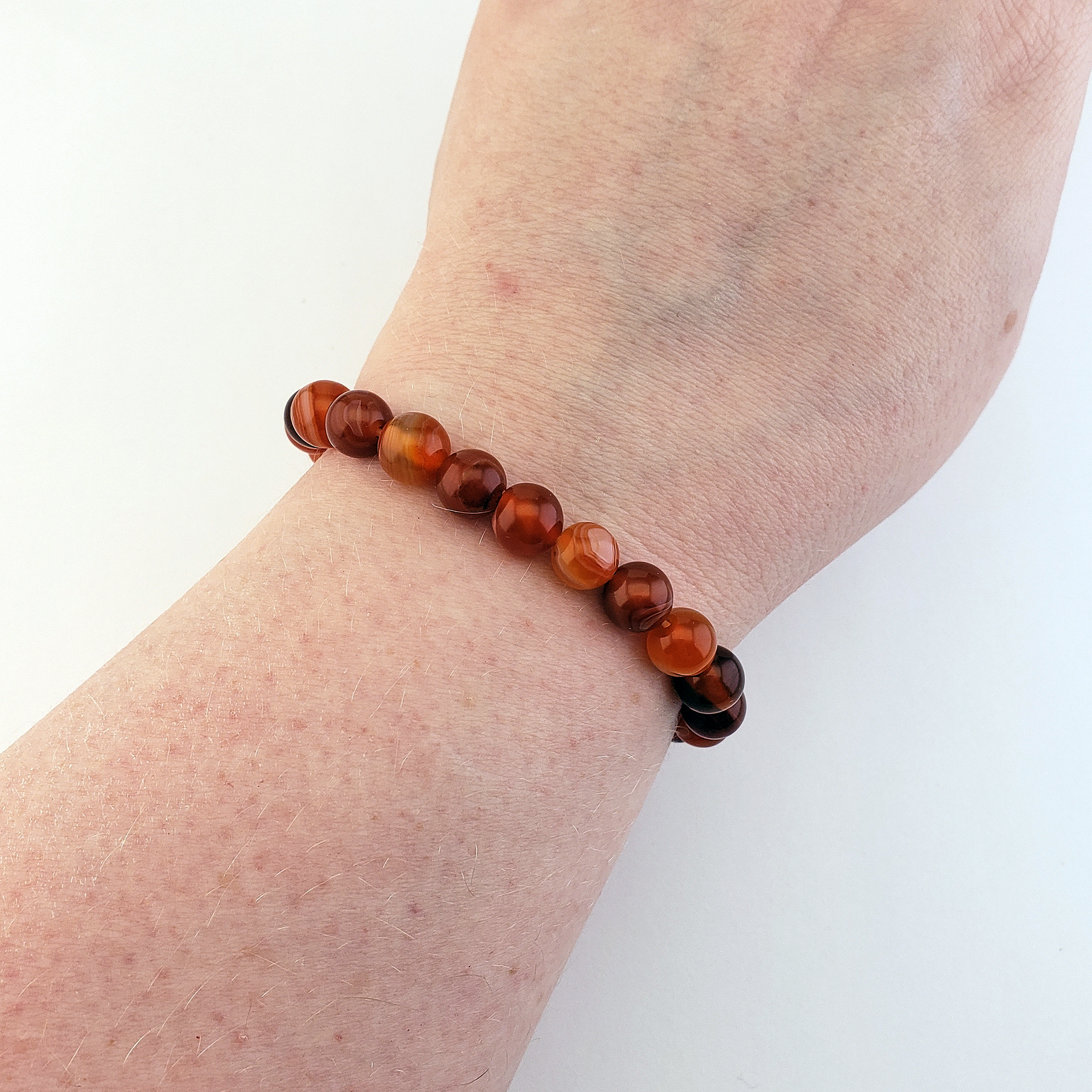 Natural Red Agate Crystal 7-8mm Bead Bracelet - On Wrist Over White Background