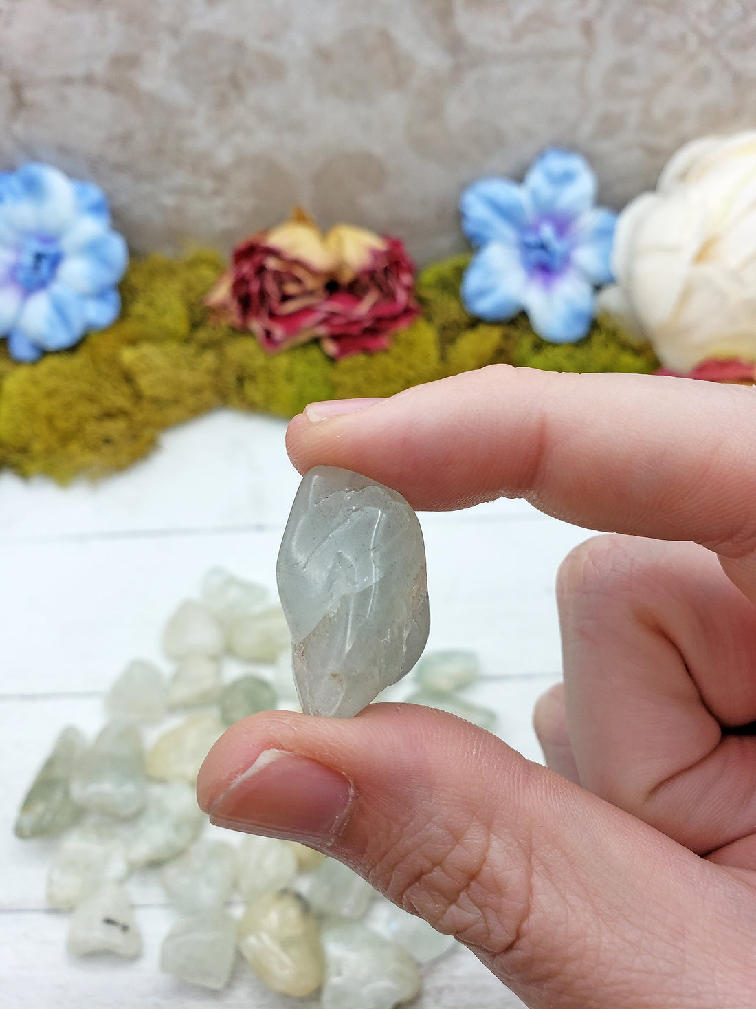 tumbled aquamarine stone pinched in hand