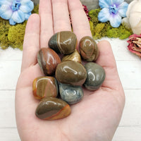 hand holding tumbled polychrome jasper stone pieces