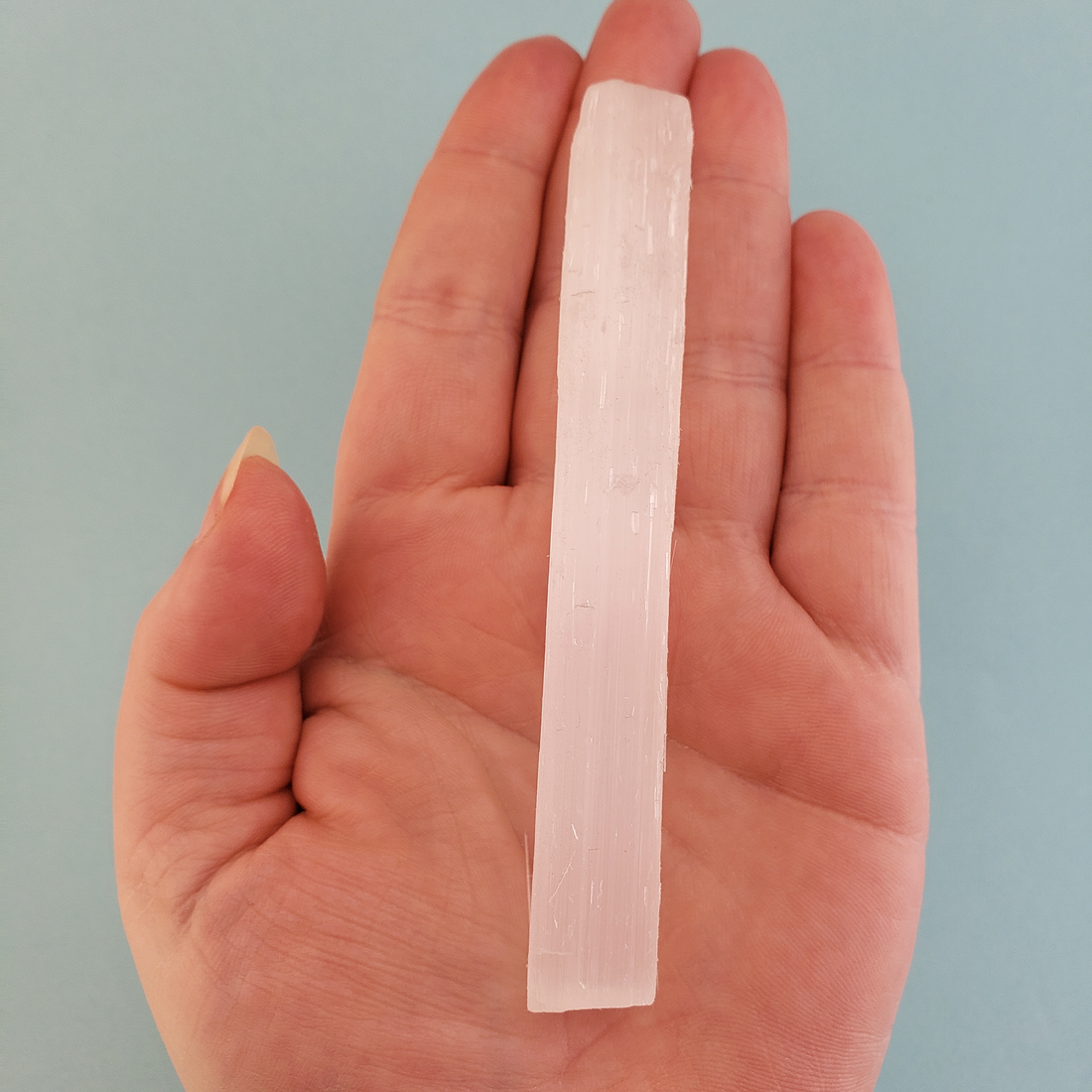 Rough Selenite Crystal Rough Stick - One 3.75 Inch Stick - Against Blue Background