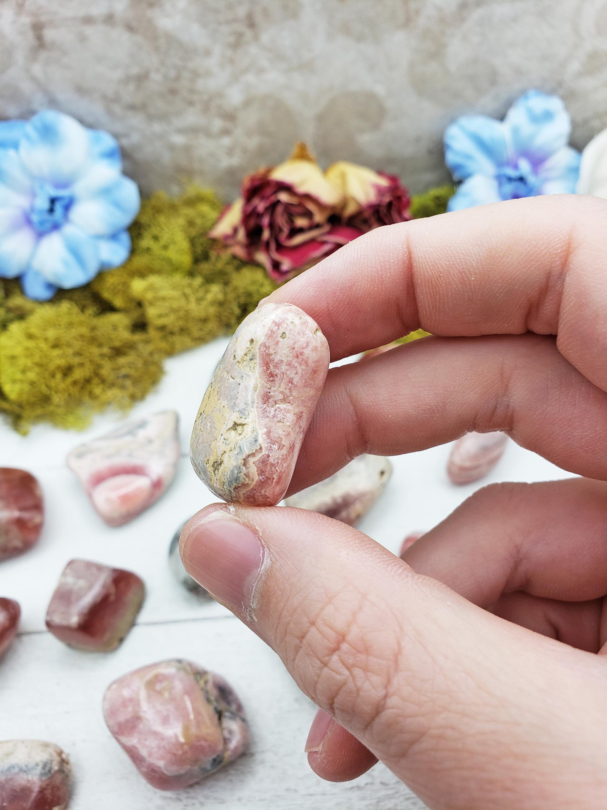 Hand pinching rhodocrosite crystal