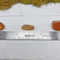ruler comparing size of 3 tangerine aura quartz pieces
