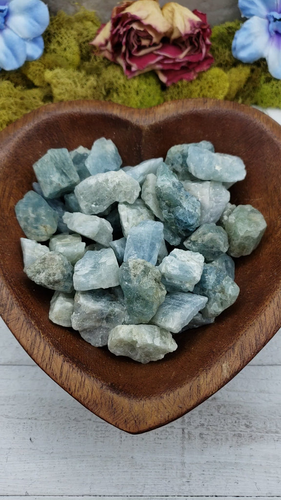 rough aquamarine stones in heart-shaped bowl