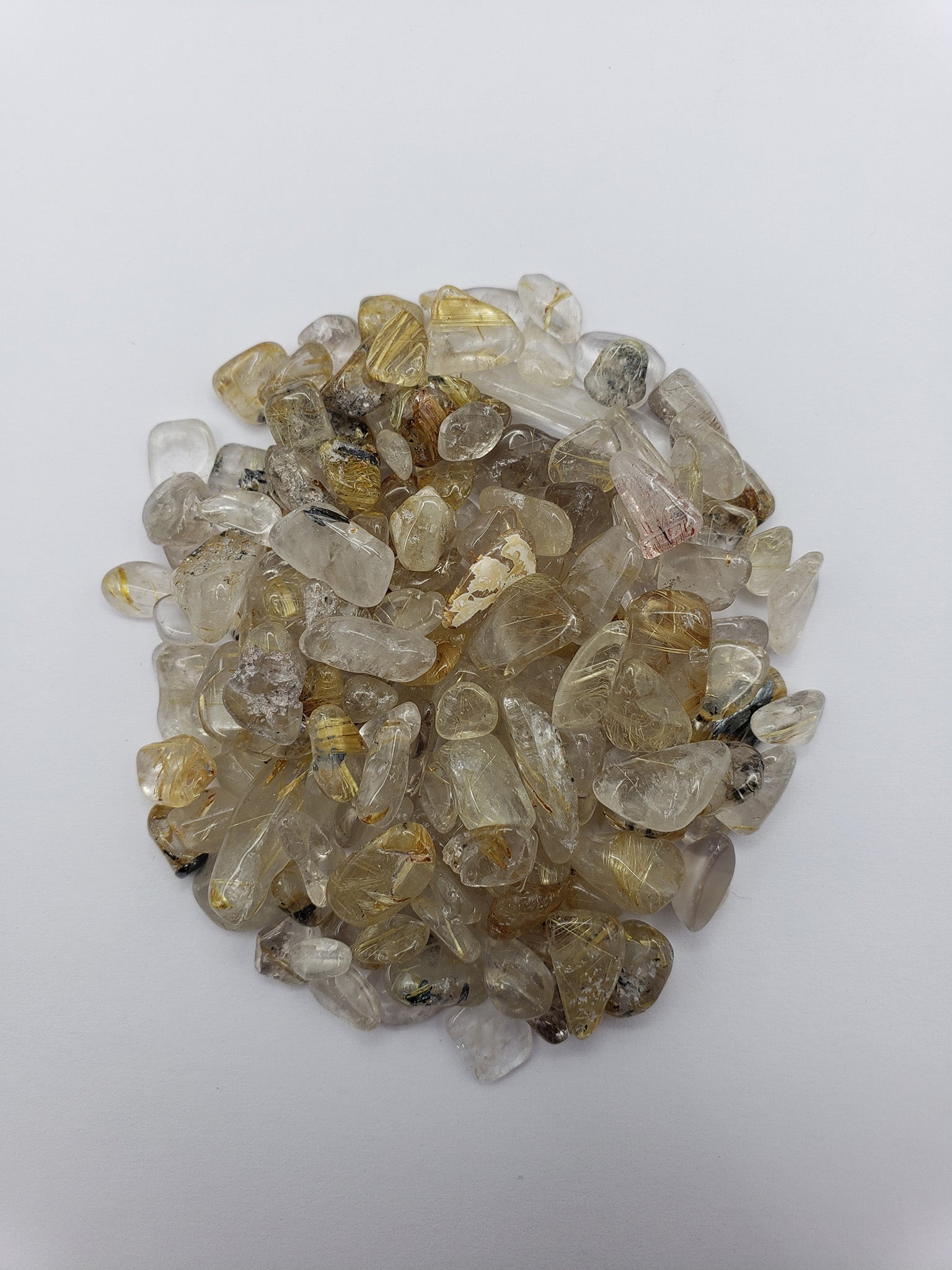 One ounce gold rutilated quartz chips on white background