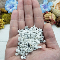 Hand holding one ounce of howlite chips