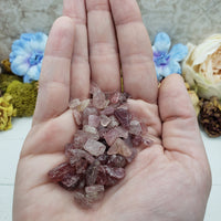 hand holding one ounce of strawberry quartz chips