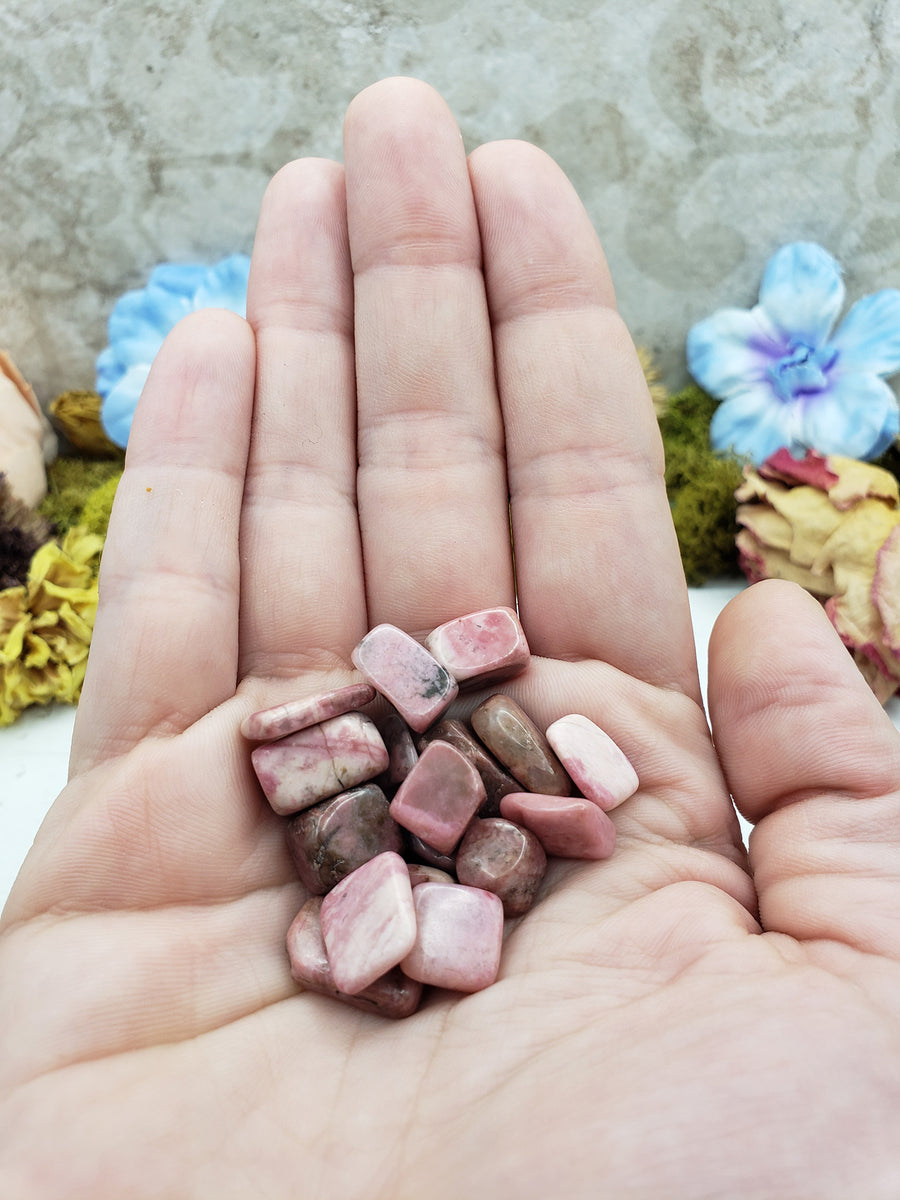 Hand holding one ounce of rhodonite crystal chips