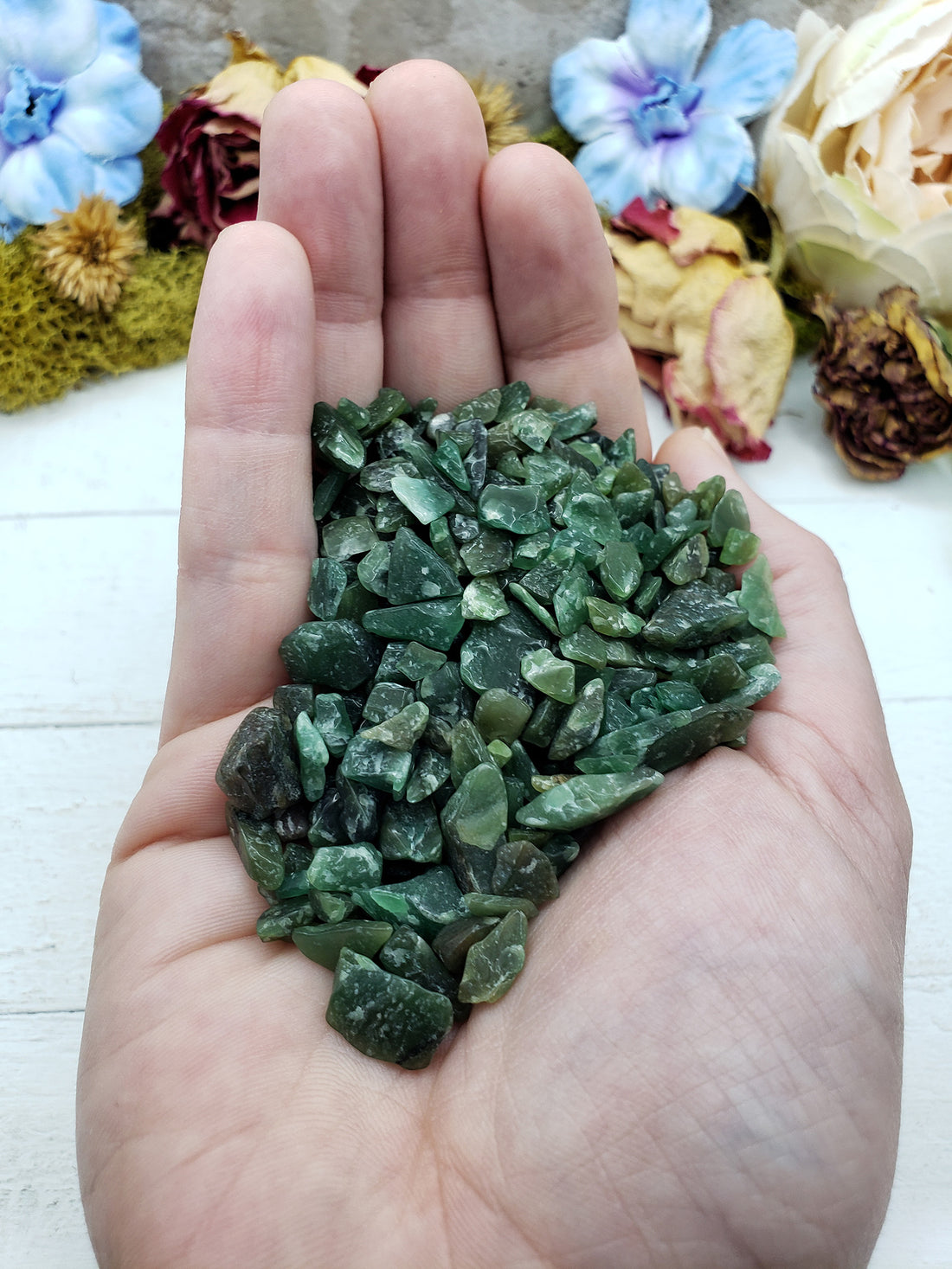 Hand holding three ounces of green aventurine chips