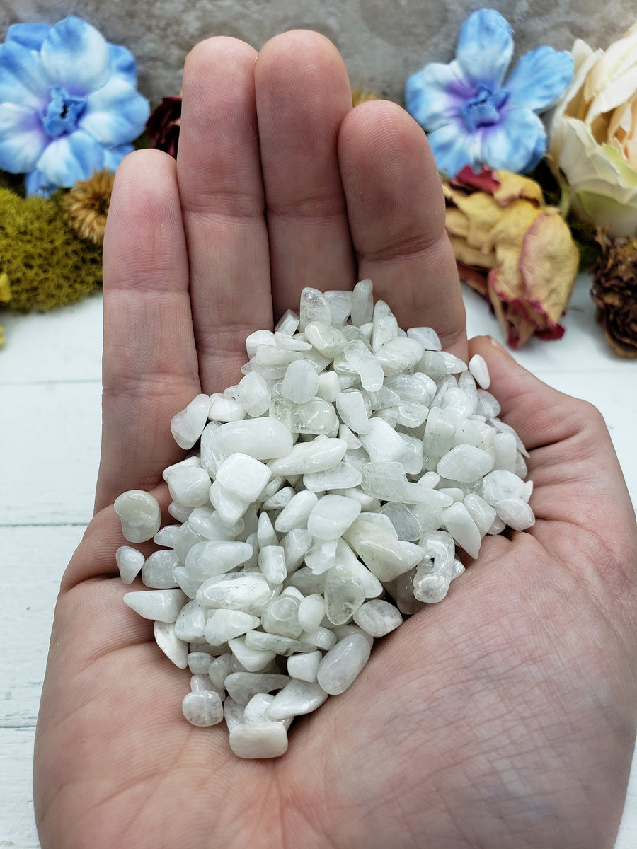Hand holding three ounces of rainbow moonstone chips