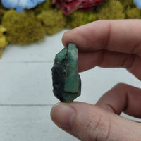 video of rough emerald stone in hand, showing off various sides