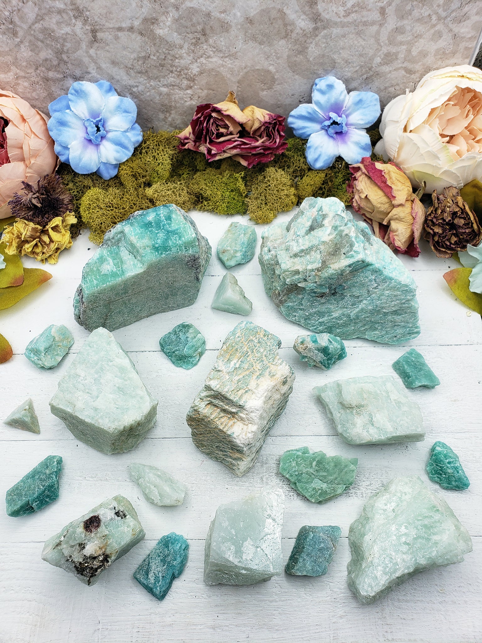 Rough amazonite crystal stones on display, spread out showing various sizes