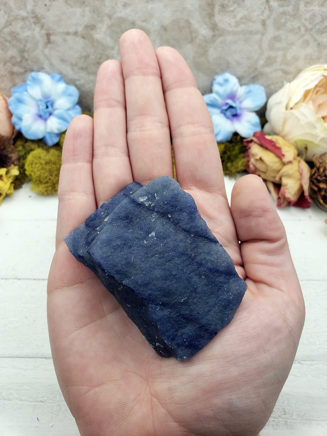 hand holding deep blue rough blue quartz crystal