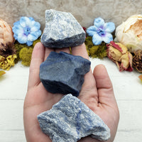 hand holding three rough blue quartz stone chunks