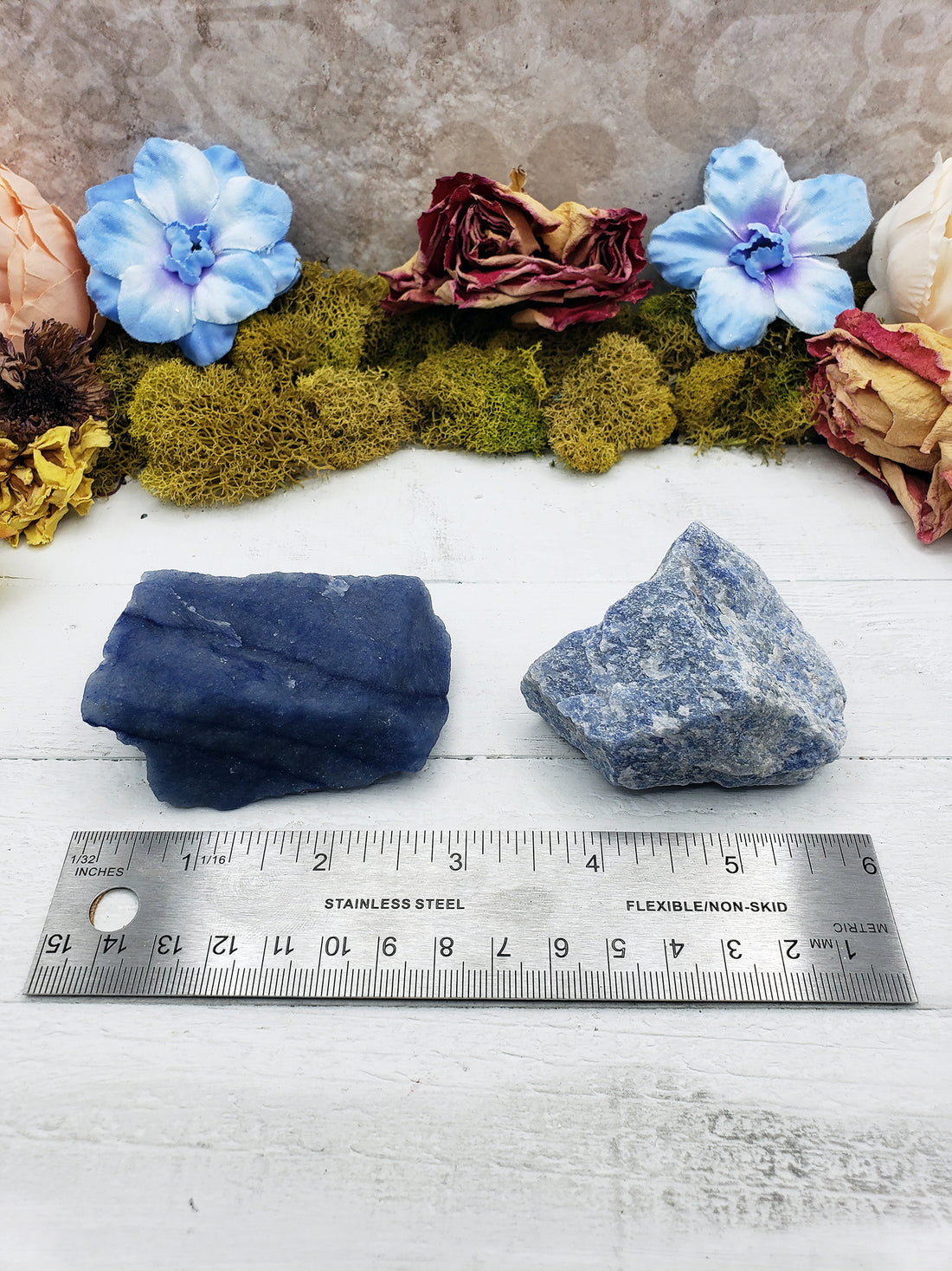Ruler comparing two rough blue quartz crystal stones, one is deep blue and the other is light blue
