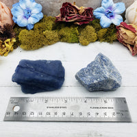 Ruler comparing two rough blue quartz crystal stones, one is deep blue and the other is light blue