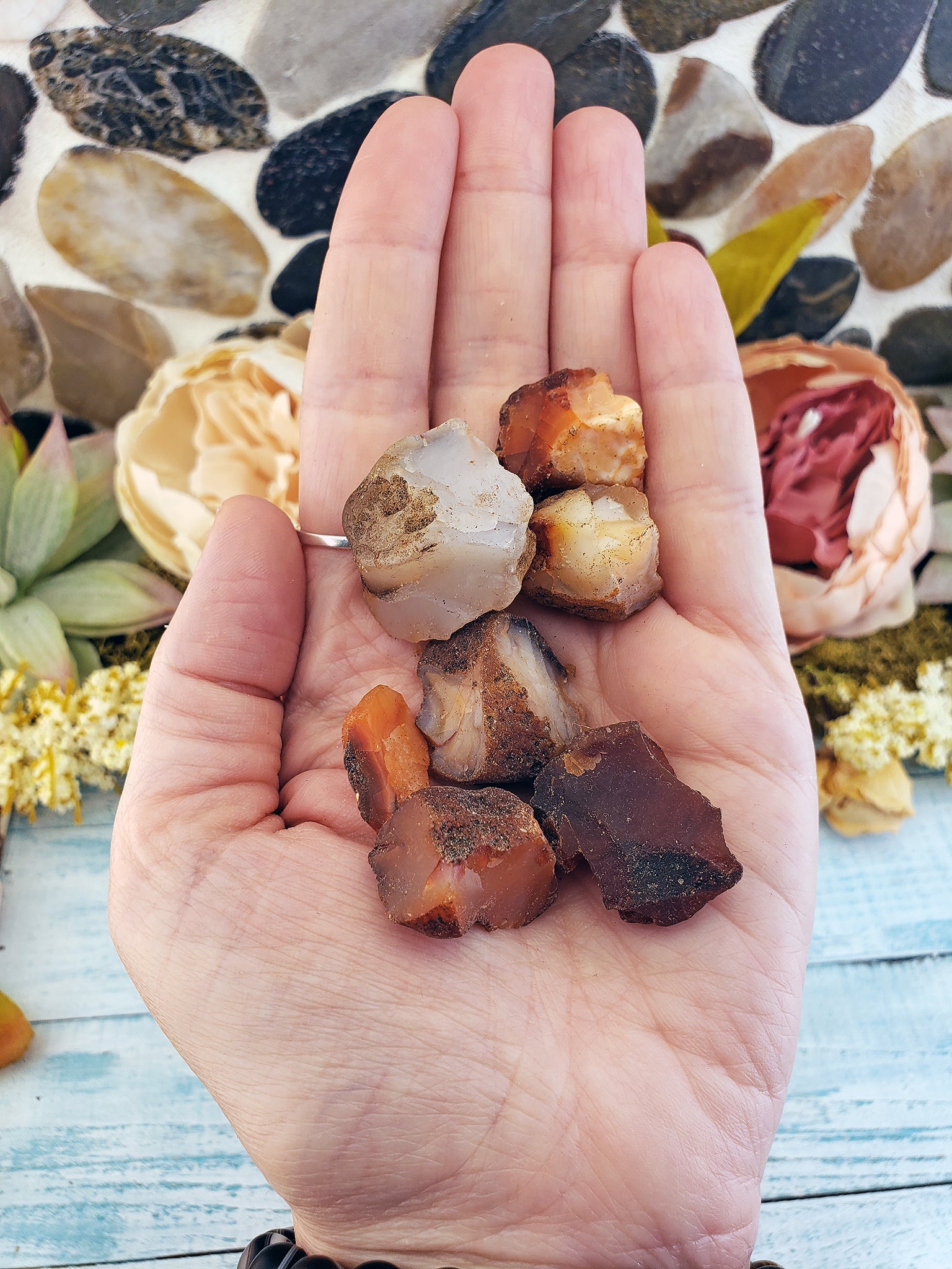 hand holding various carnelian crystal pieces