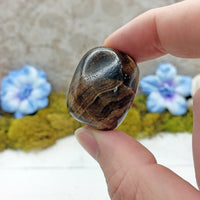 hand pinching Chocolate brown calcite stone