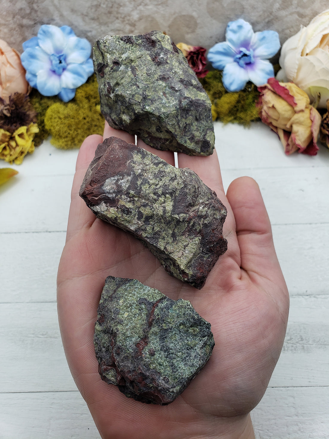 three rough dragon stone pieces in hand