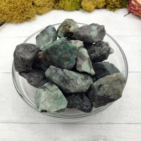rough emerald stone pieces in bowl