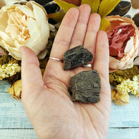 two rough epidote crystal pieces in hand