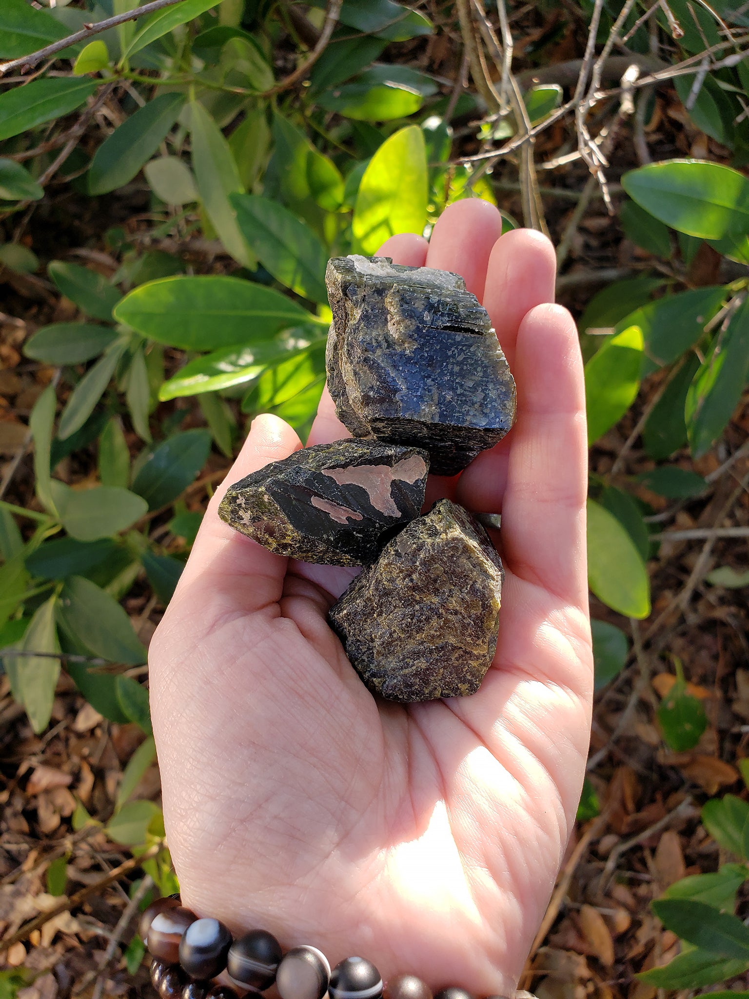 rough epidote pieces in hand