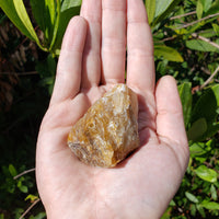 hand holding rough fire quartz crystal in sunlight