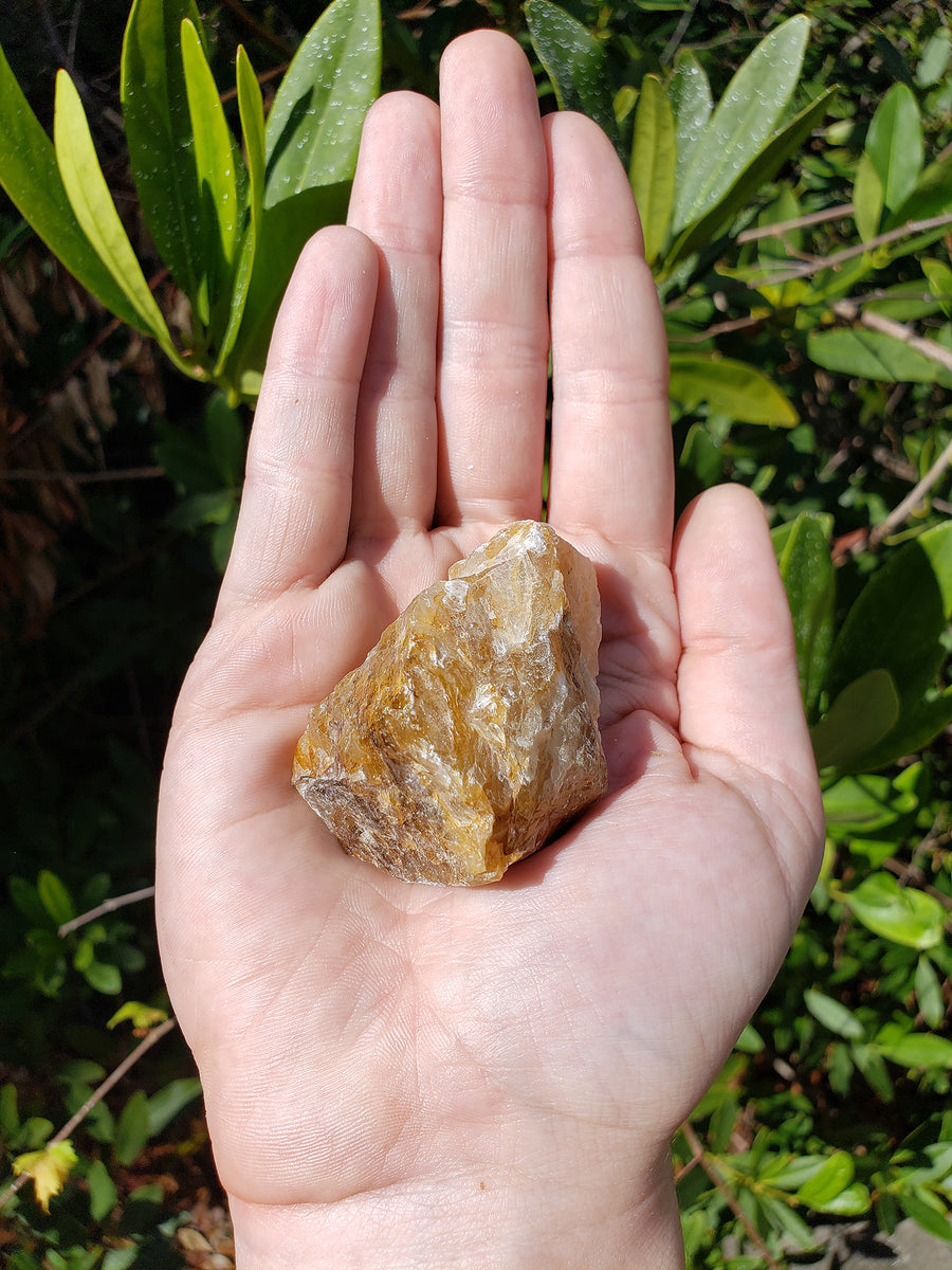 hand holding rough fire quartz crystal in sunlight
