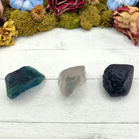 three rough fluorite crystal stones on display