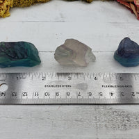 rough fluorite crystal pieces by a ruler, showing measurement comparison
