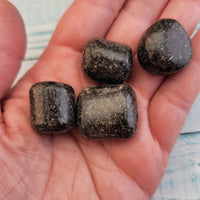 Tumbled green nuummite coppernite stones in hand